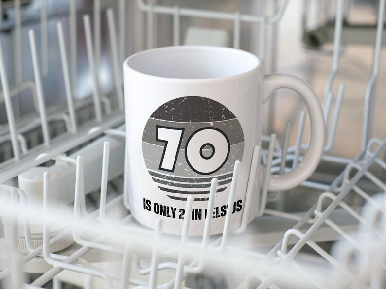 A white 11-ounce ceramic mug with a comfortable C-handle and rounded edges. The black and white design displays the words 70 Is Only 21 in Celsius.