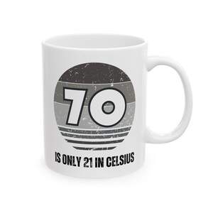 White ceramic mug featuring a vintage-style circular graphic with the number “70” and the text “Is only 21 in Celsius” in black lettering.