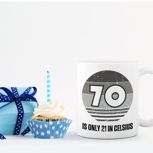 A white 11-ounce ceramic mug with a comfortable C-handle and rounded edges. The black and white design displays the words 70 Is Only 21 in Celsius.