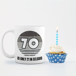 A white 11-ounce ceramic mug with a comfortable C-handle and rounded edges. The black and white design displays the words 70 Is Only 21 in Celsius.