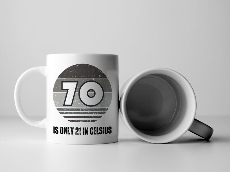 A white 11-ounce ceramic mug with a comfortable C-handle and rounded edges. The black and white design displays the words 70 Is Only 21 in Celsius.