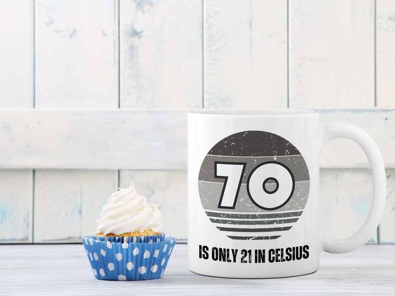 A white 11-ounce ceramic mug with a comfortable C-handle and rounded edges. The black and white design displays the words 70 Is Only 21 in Celsius.