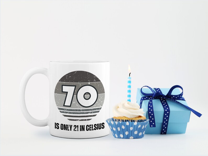 A white 11-ounce ceramic mug with a comfortable C-handle and rounded edges. The black and white design displays the words 70 Is Only 21 in Celsius.