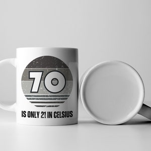 A white 11-ounce ceramic mug with a comfortable C-handle and rounded edges. The black and white design displays the words 70 Is Only 21 in Celsius.
