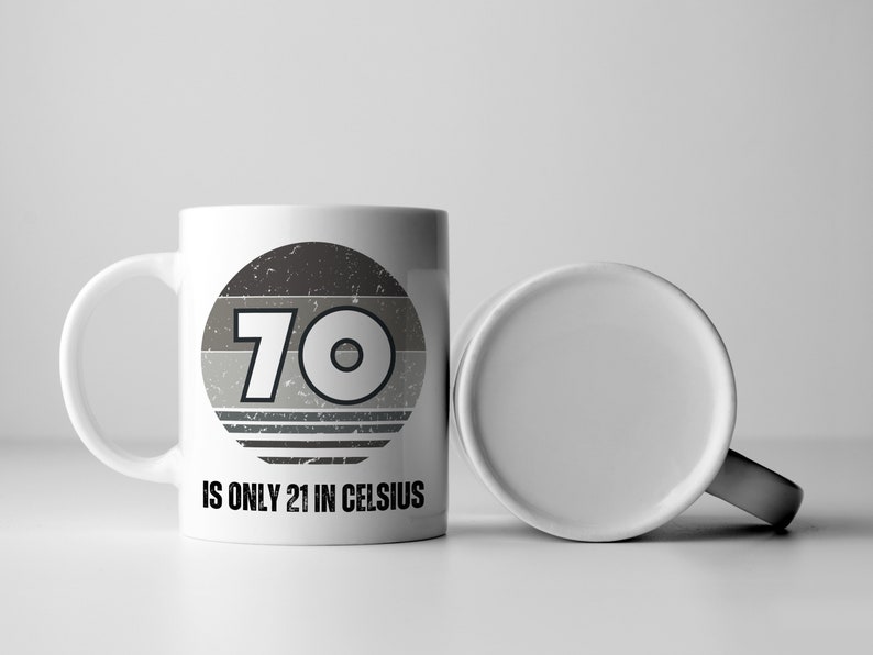 A white 11-ounce ceramic mug with a comfortable C-handle and rounded edges. The black and white design displays the words 70 Is Only 21 in Celsius.