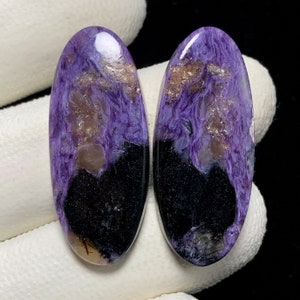 Può includere: Un paio di pietre preziose cabochon ovali con un motivo a marmi viola e nero. Le pietre hanno un'alta lucidatura e sono pronte per essere incastonate in gioielli.