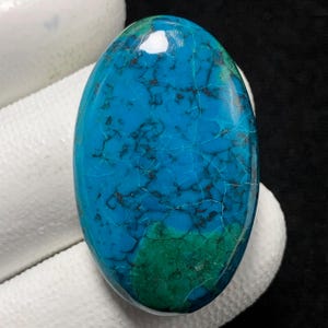 May include: A large, oval-shaped turquoise cabochon with a blue and green colour pattern. The stone has a smooth, polished surface and a natural, organic look.