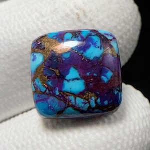 May include: A square cabochon of turquoise, purple, and gold. The stone has a marbled pattern with swirls of blue, purple, and gold.