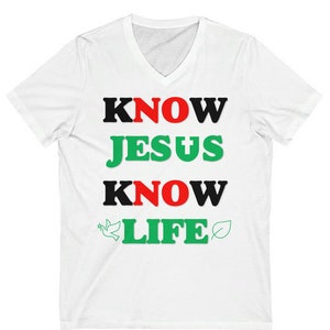May include: White V-neck t-shirt with the text "KNOW JESUS KNOW LIFE" in black, red, and green letters. A dove and a leaf are on either side of the word "LIFE".