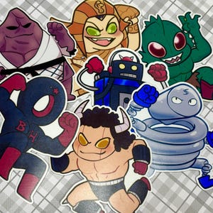 Op de afbeelding: Een set van acht kleurrijke cartoonfiguur stickers. De stickers tonen een paarse creatie met een wit karatepak, een gele creatie met een kroon, een groene creatie met rode ogen, een blauwe robot met bokshandschoenen, een zwart-rode creatie met een ster op zijn hoofd, een bruine creatie met hoorns, een grijze creatie met een veerlichaam en een witte creatie met een bliksem op zijn hoofd.