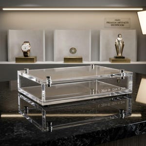 May include: A rectangular clear acrylic display case with silver-toned metal hardware at each corner. The side of the case features printed text reading L: 26cm W: 12cm H: 2cm, indicating the physical dimensions of the transparent storage box.