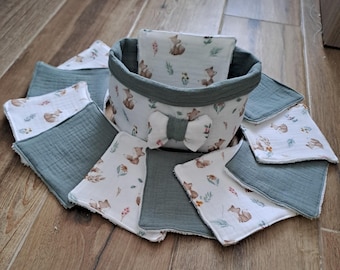 May include: A set of 10 reusable cotton rounds in a green and white fabric basket. The rounds have a white background with a small fox and floral print. The basket has a white bow and a green fabric lining.