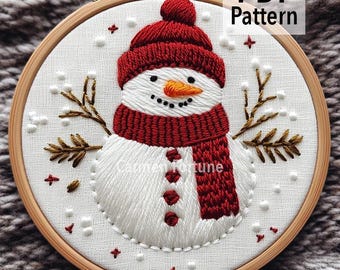 Könnte beinhalten: Gestickter Schneemann in einem Holzreifen. Der Schneemann trägt einen roten Hut und Schal, mit einer Karottennase und schwarzen Knopfaugen. Das Design beinhaltet Schneeflocken und Zweige. Der Text "PDF Pattern" ist sichtbar.