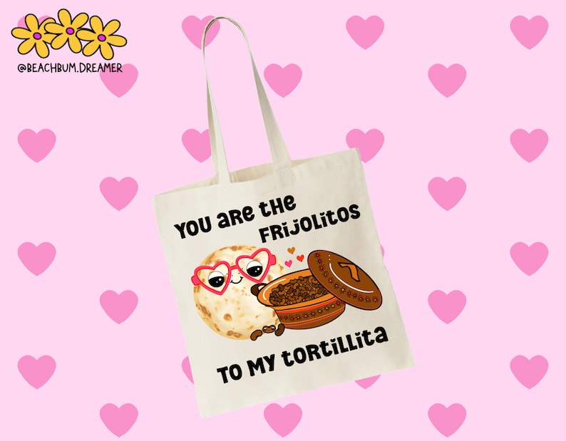May include: A white tote bag with a cartoon illustration of a tortilla with heart-shaped sunglasses and a pot of frijoles. The text on the bag reads "You are the Frijolitos to my Tortillita."