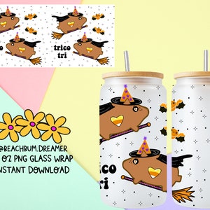 May include: A set of two 16 ounce glass tumblers with a white background and a repeating pattern of a brown guinea pig wearing a witch's hat and riding a broomstick. The guinea pig is holding a candy corn. The pattern also includes bats and stars. The tumblers have a bamboo lid and a straw.
