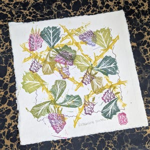 May include: A square print featuring a botanical design of blackberries and leaves in shades of green, purple, and yellow. The print includes the text "bramble patch" and a small red stamp with the initials "KH" and the number "20".