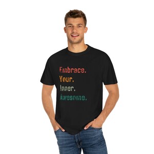 Puede incluir: Una camiseta negra con un gráfico de estilo vintage que dice "Embrace. Your. Inner. Awesome."