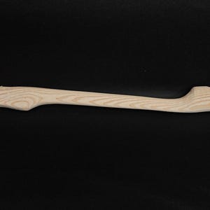 May include: A plain wooden axe handle with a natural finish. The handle is curved and has a slight taper.