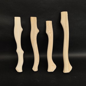 Könnte beinhalten: Vier Holz-Axt-Stiele mit natürlicher Holzmaserung. Die Stiele sind alle in verschiedenen Formen und Größen.