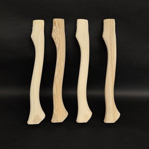 Könnte beinhalten: Vier unfertige Axt-Stiele aus Holz, jeder mit einem einzigartigen Maserungsmuster. Die Stiele sind alle gleich groß und gleich geformt und in einer Reihe angeordnet.