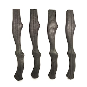 Könnte beinhalten: Vier schwarze Holzstuhlbeine mit einem einzigartigen geschwungenen Design. Die Beine sind aus dunklem Holz mit einer natürlichen Maserung.