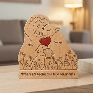 May include: Wooden family lion sculpture with engraved names "Billy", "Nancy", "Lucas", and "Chloe". A red heart is between the lion and lioness. The base reads "Where life begins and love never ends". The sculpture features floral and grass details.