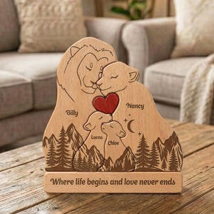 May include: Wooden family lion sculpture with names Billy, Nancy, Lucas, and Chloe. A red heart is between the parents. The base reads "Where life begins and love never ends." The sculpture is on a wooden table.