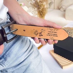 May include: A brown leather belt with a silver buckle. The belt is engraved with the words "I Fucking Love you" and a stick figure illustration. The text also includes "(EITHER WAY WORKS) THINK OF ME WHENEVER YOU TAKE OFF YOUR PANTS!" and the name "Sophia".