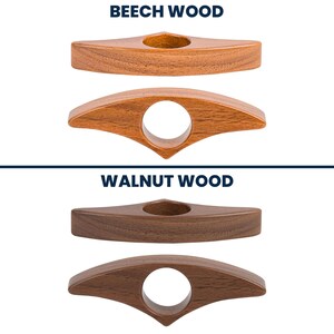 May include: Two wooden thumb page holders, one in beech wood and one in walnut wood. The beech wood holders are light brown, and the walnut wood holders are dark brown. Each has a finger hole and a triangular top.