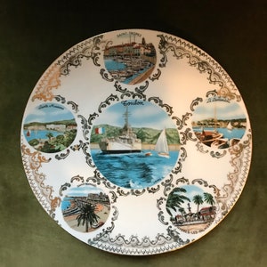 Peut inclure: Assiette en céramique blanche avec un bord doré et un motif décoratif. L'assiette présente des images de différentes villes françaises, notamment Saint-Tropez, Toulon, Sainte-Maxime, Saint-Raphaël et Hyères-les-Palmiers.