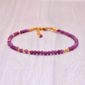 May include: A delicate pink gemstone bracelet with gold beads and a sliding clasp.