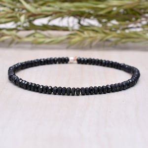 May include: A black gemstone beaded bracelet with a silver clasp.