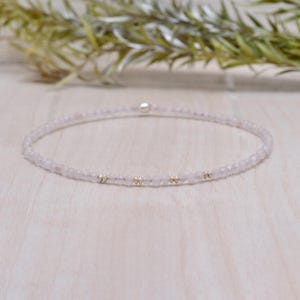 Puede incluir: Un delicado collar de cuarzo rosa con pequeñas cuentas doradas. El collar está hecho de pequeñas cuentas de cuarzo rosa facetadas y está enhebrado en una fina cadena de plata.