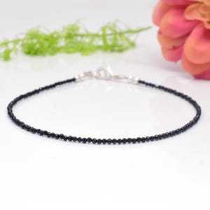 May include: A delicate black gemstone bracelet with a silver clasp. The bracelet is made of small, round black beads and is perfect for everyday wear.