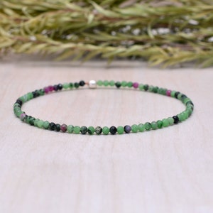 May include: A delicate green, black and pink gemstone bracelet with a silver clasp.