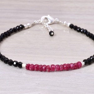 Puede incluir: Un brazalete delicado con cuentas de piedras preciosas negras y rojas. El brazalete está hecho de plata y tiene un cierre de langosta.