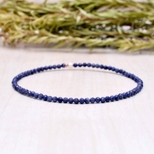 May include: A delicate blue gemstone bracelet made with small, faceted beads. The bracelet is strung on a silver chain and has a simple, elegant design.