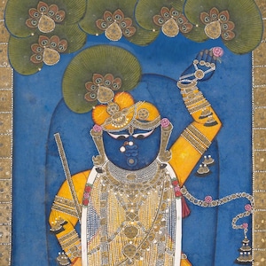 May include: An Indian miniature painting depicting a deity with blue skin, adorned in gold jewelry and a yellow garment. The figure holds a pink flower, set against a blue backdrop with decorative elements and green foliage.