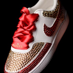 May include: White sneakers with red and gold rhinestones, red satin laces, and the word "Noiva" on the side.