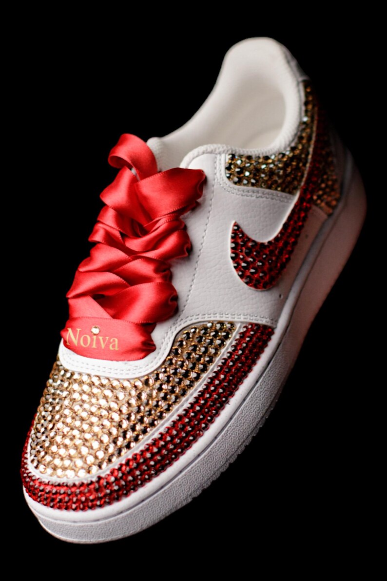 May include: White sneakers with red and gold rhinestones, red satin laces, and the word "Noiva" on the side.