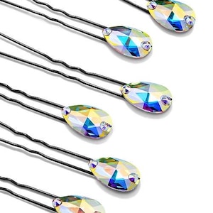 Puede incluir: Seis horquillas negras, cada una adornada con un cristal iridiscente en forma de lágrima. Los cristales reflejan un espectro de colores, incluyendo amarillo, azul y verde, sobre un fondo blanco. Accesorios para el cabello.