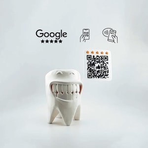 Può includere: Vaso da fiori in ceramica bianca a forma di dente sorridente con una fila di denti. Il vaso è su una superficie bianca. Il logo Google con cinque stelle e un codice QR sono visibili sullo sfondo.