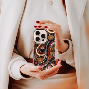 Hand holding phone showcasing an Aboriginal dot art phone case, kangaroo and dot painting design seen in lifestyle use