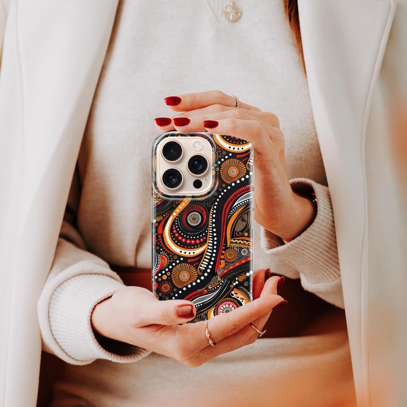 Hand holding phone showcasing an Aboriginal dot art phone case, kangaroo and dot painting design seen in lifestyle use