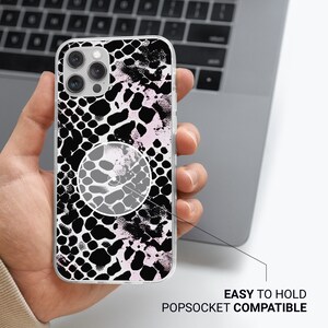 May include: A clear phone case with a black and white snake skin pattern and a pink accent. The case is compatible with a popsocket.