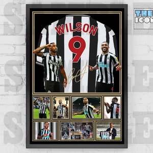 May include: A framed black and white photo of a soccer player wearing a black and white jersey with the number 9 and the name "Wilson" on the back. The photo is surrounded by a black frame with a gold border. The photo includes multiple images of the player in different poses.