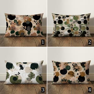 May include: Four rectangular throw pillows with abstract designs. Pillows feature patterns of black, green, and tan shapes on a neutral background. Each pillow has a different design, with variations in the arrangement of the shapes.