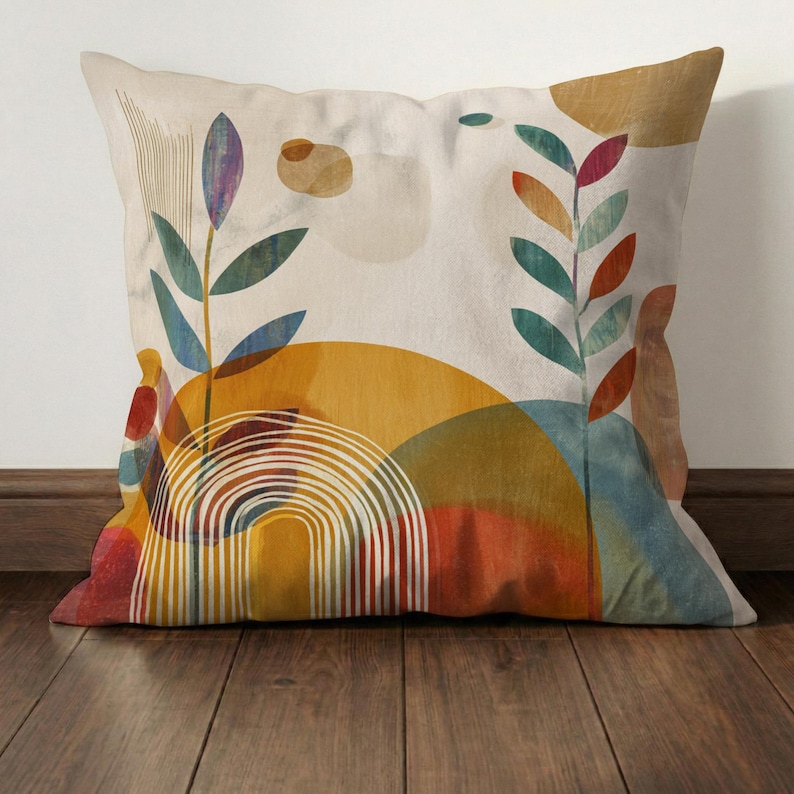 May include: Square decorative pillow with an abstract design. The pillow features a cream background with colorful shapes, including a yellow sun, a rainbow, and green and blue leaves. The pillow is placed on a wooden floor.