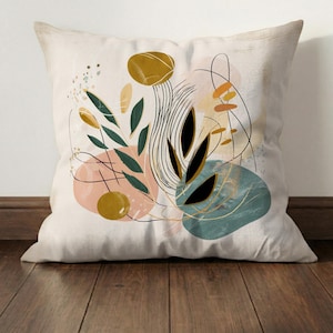 May include: Square throw pillow with an abstract design. The pillow features a cream-colored background with a colorful, artistic design. The design includes black, green, gold, pink, and teal shapes and lines, creating a modern aesthetic.