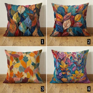 Könnte beinhalten: Vier quadratische Kissen mit bunten Blättermustern. Jedes Kissen hat ein einzigartiges Design mit leuchtenden Farbtönen von Rot, Orange, Gelb, Blau und Grün. Die Kissen sind auf einer Holzoberfläche angeordnet.